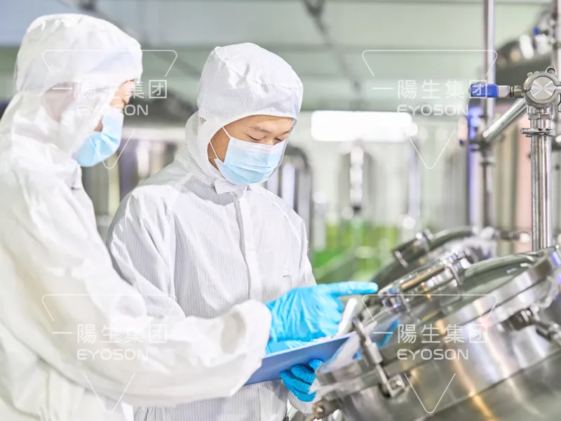 Two staff members recording data and operating fermentation equipment in a sterile workshop environment.